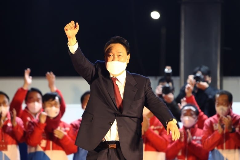 A man in a white mask and suit.