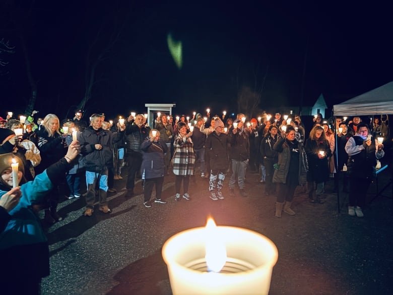 People standing in a circle holding candles.