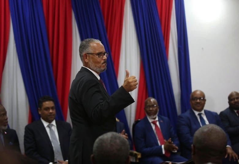 A man gives the thumbs-up during a ceremony.