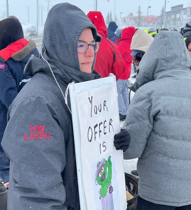 A woman holding a picket sign that reads "your offer is" followed by an illustration of a green muppet in a trash can.