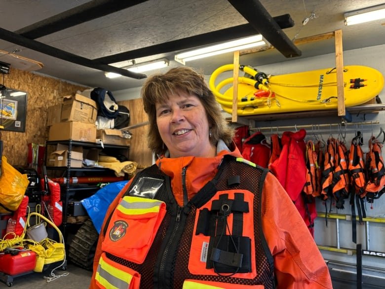 A woman wears a bright orange safety vest.