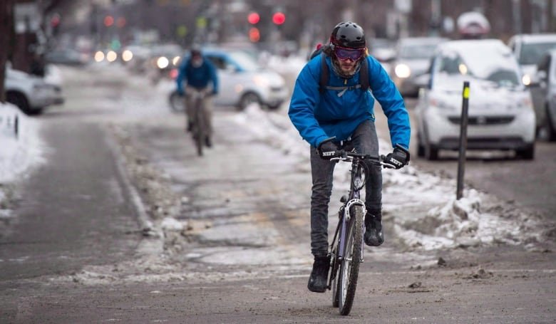 A cyclist rides their bike on a path during winter.