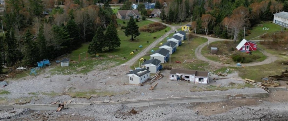 An aerial photo Glenghorm Beach Resort that shows damage to two cabins, an out building, playground, and a seawall.