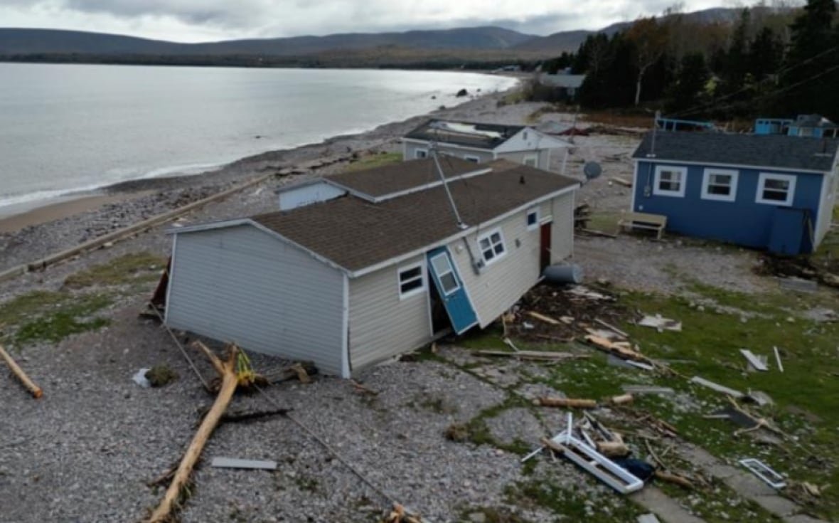 A damaged building at Glenghorm Beach Resort surrounded by debris with the ocean in the background.