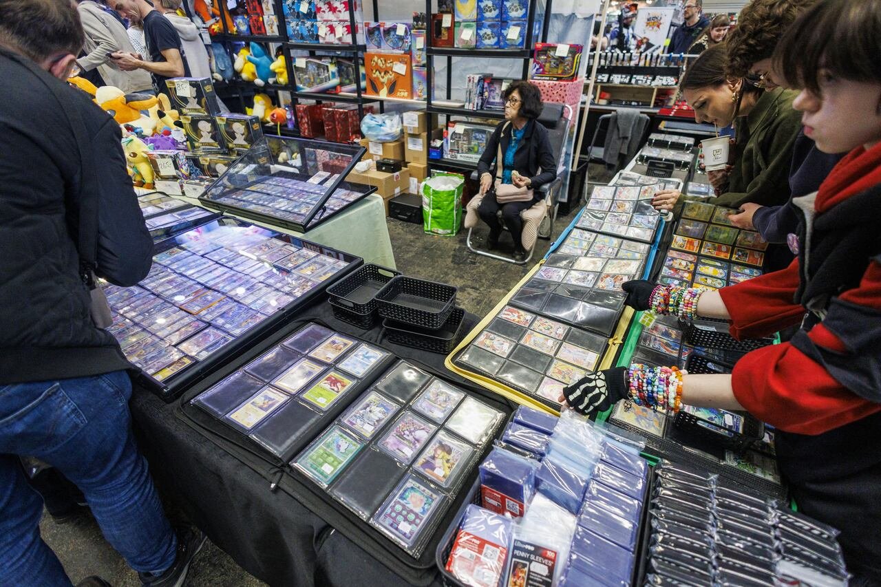 People look at tables full of Pokemon cards.